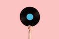 Girl hand showing retro vinyl gramophone record on pink background, closeup Royalty Free Stock Photo