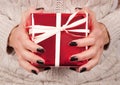 Girl hands with black nail and sweater holds red gift box Royalty Free Stock Photo