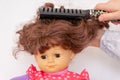 Girl hands combing hair of female doll