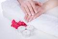 Girl hands with french manicure modern style on towel with red rose petals and candle in beauty salon Royalty Free Stock Photo