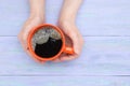 Girl hands hold an orange cup of coffee on a blue wooden background. View from above Royalty Free Stock Photo