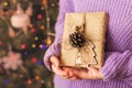 girl holding small gift in her hands. decorated Christmas tree on background. Bright Christmas card with space for text Royalty Free Stock Photo