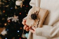 girl holding small gift in her hands. decorated Christmas tree on background. Bright Christmas card with space for text Royalty Free Stock Photo
