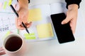 Girl Hands With Mobile Phone With Calendar Writing And List Of Work In Diary On Desk