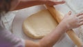 Girl hands rolling dough on table with mother at kitchen. Family cooking at home