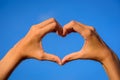 Girl hands in shape of love heart on blue sky Royalty Free Stock Photo