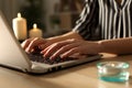 Girl hands typing on laptop on power outage with candles