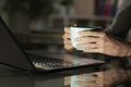 Girl hands watching media on laptop at night with coffee Royalty Free Stock Photo