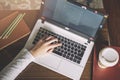 Girl hands working on modern laptop. Desktop, book, pen, coffee on background