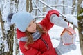 Girl hangs bird feeder in winter snowy forest