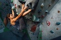 The girl hangs on the ledges climbing the wall in training room