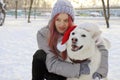 The girl happily communicates with the dog in the hat of Santa Claus