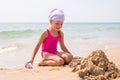 Girl happily looks at sand pit dug up, sitting on the beach Royalty Free Stock Photo