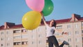 A girl happily poses with large with colorful balloons in the city. Royalty Free Stock Photo