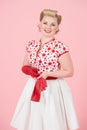 A Girl happiness blonde with red long gloves on pastel pink background. Pretty curls woman with pin-up make-up isolated in studio. Royalty Free Stock Photo