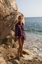 Girl with harpoon in flannel shirt on the rocky beach Royalty Free Stock Photo