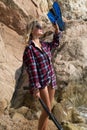 Girl with harpoon in flannel shirt on the rocky beach Royalty Free Stock Photo