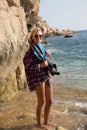 Girl with harpoon in flannel shirt on the rocky beach Royalty Free Stock Photo