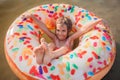 Girl has fun on big donut inflatable ring on lake on hot summer day, happy summertime, countryside Royalty Free Stock Photo