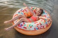 Girl has fun on big donut inflatable ring on lake on hot summer day, happy summertime, countryside Royalty Free Stock Photo