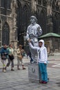 A girl has her photograph taken with a statue street performer painted in silver in Vienna in Austria.