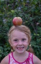 The girl has a large, ripe, appetizing apple on her head. Royalty Free Stock Photo