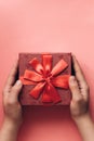 The girl has received a gift in a beautiful red box with a ribbon and is going to open it. Royalty Free Stock Photo