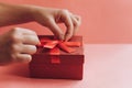 The girl has received a gift in a beautiful red box with a ribbon and is going to open it. Royalty Free Stock Photo