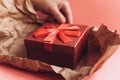 The girl has received a gift in a beautiful red box with a ribbon and is going to open it. Royalty Free Stock Photo