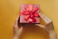 The girl has received a gift in a beautiful red box with a ribbon and is going to open it. Royalty Free Stock Photo