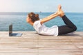 Girl has a yoga practice on the wooden floor with laptop