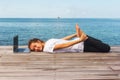 Girl has a yoga practice on the wooden floor with laptop