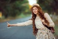 Girl with hat and backpack hitchhiking on the road Royalty Free Stock Photo