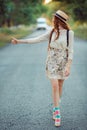 Girl with hat and backpack hitchhiking on the road