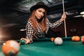 A girl in a hat in a billiard club with a cue and balls in her hands.Playing pool Royalty Free Stock Photo