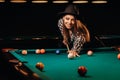 A girl in a hat in a billiard club with a cue in her hands hits a ball.Playing billiards Royalty Free Stock Photo