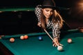 A girl in a hat in a billiard club with a cue in her hands hits a ball.Playing billiards Royalty Free Stock Photo