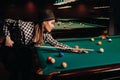 A girl in a hat in a billiard club with a cue in her hands hits a ball.Playing pool Royalty Free Stock Photo