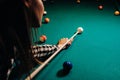 A girl in a hat in a billiard club with a cue in her hands hits a ball.Playing pool Royalty Free Stock Photo