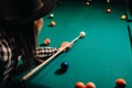 A girl in a hat in a billiard club with a cue in her hands hits a ball.Playing pool Royalty Free Stock Photo