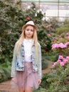 Girl in a hat and a denim jacket walks in a flowering garden