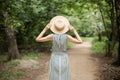 Girl in a hat and dress walking in the forest