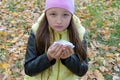 The girl in the hat and jacket sneezes and wipes her nose with a napkin in the autumn forest while walking. Flu season and cold