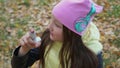 A girl in a hat and jacket takes medicine in the form of an inhaler for bronchial asthma in the autumn forest during a walk. Flu s