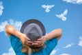 Girl in hat looks at dove birds in cloud shape soars in blue sky. Concept of love, romance and happy relations. Valentine day or