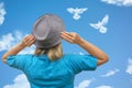 Girl in hat looks at dove birds in cloud shape soars in blue sky. Concept of love, romance and happy relations. Valentine day or