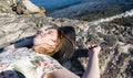A girl in a hat is lying and sunbathing on the rocks on the beach on a sunny summer day Royalty Free Stock Photo
