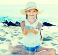 Baby girl in hat playing with sand on sea coast in summer Royalty Free Stock Photo