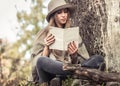 Girl in a hat reading a book in autumn forest