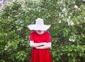 A girl in hat and red dress walking in a small garden in the countryside at summer. Royalty Free Stock Photo